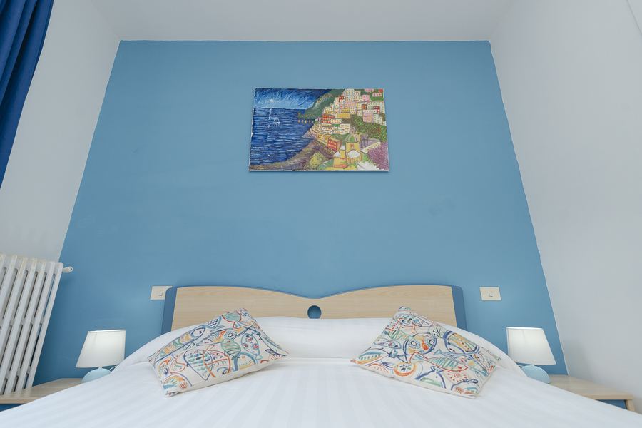 Camera con parete azzurra e quadro della Costiera Amalfitana