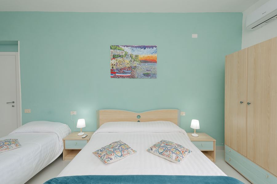 Camera con parete verde acqua, letto matrimoniale e ceramica decorata